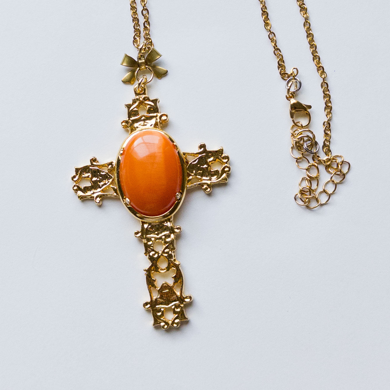 Large gold-plated cross pendant featuring an orange hue onyx stone in the center. gothic catholic ornate