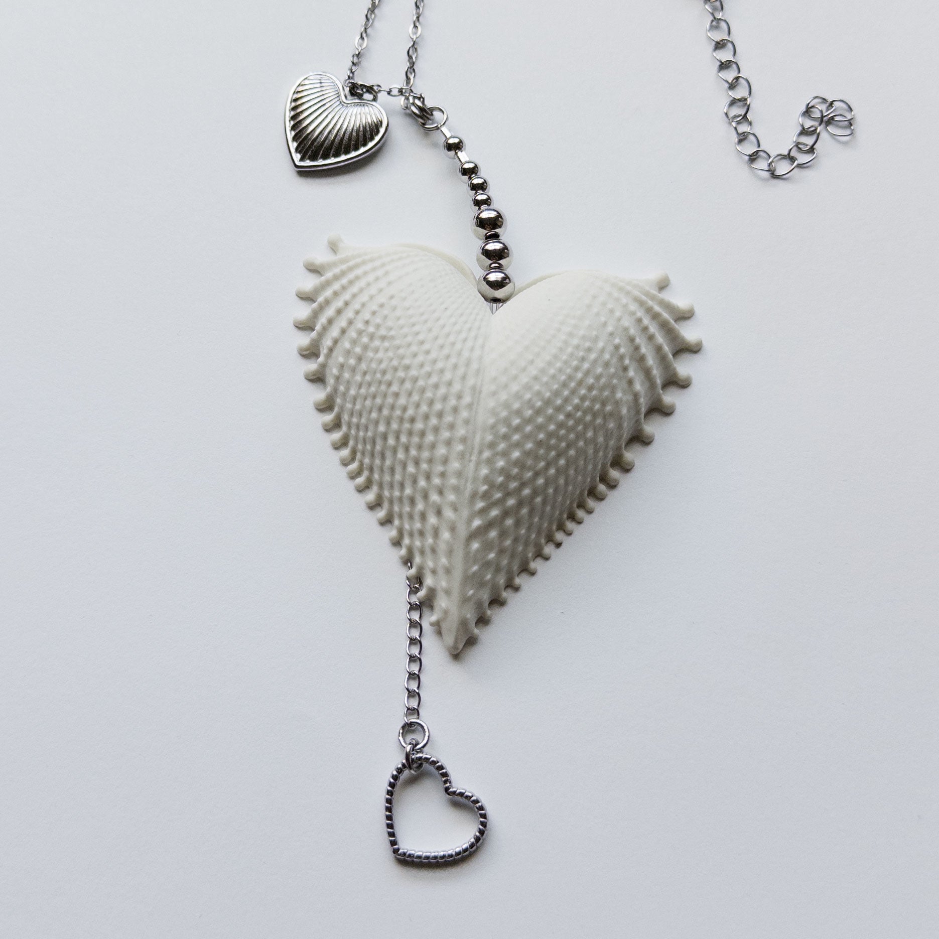 Multi charms necklace featuring a large vintage scallop heart, stainless steel heart charms, on a stainless steel chain.