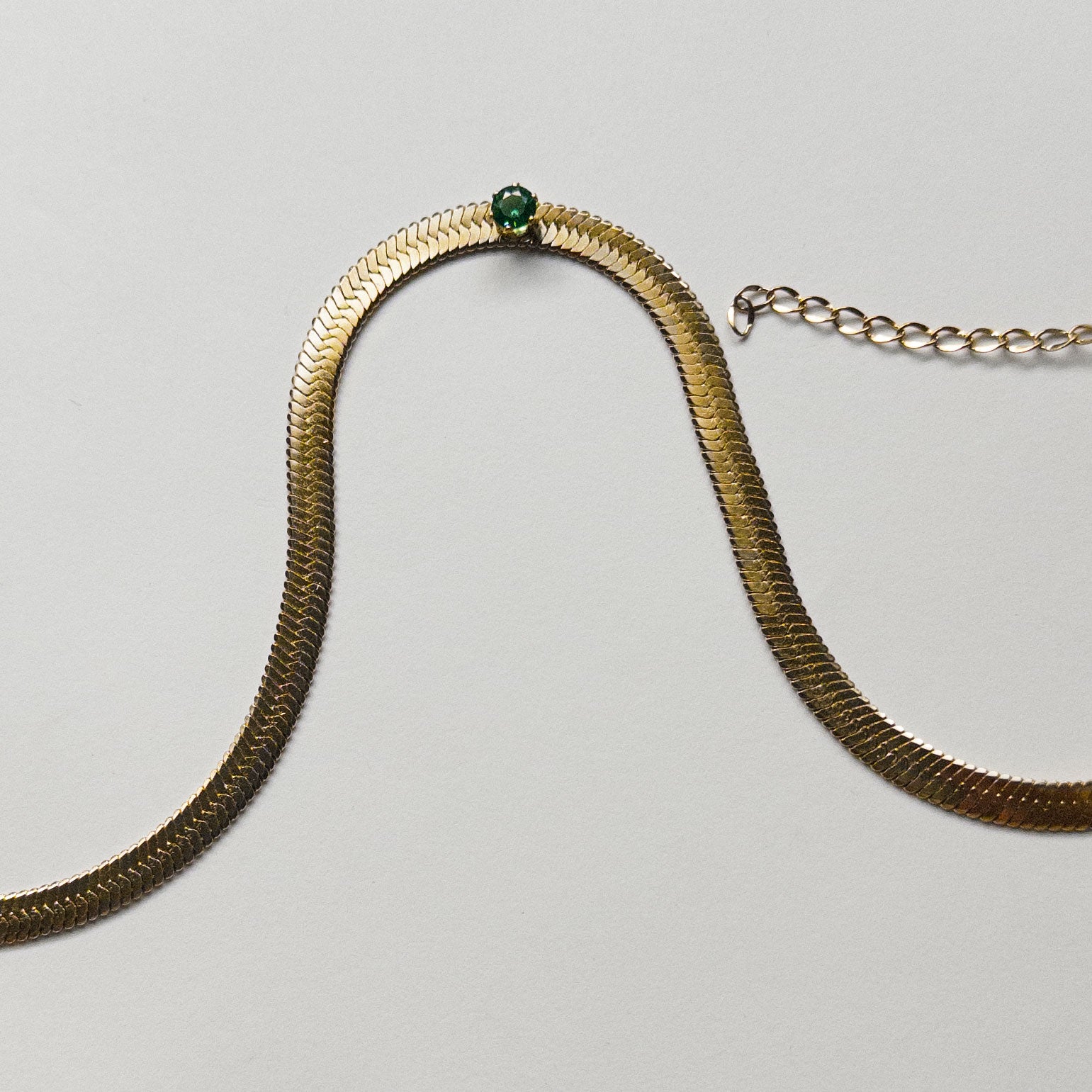 Stainless steel gold colored snake chain choker/necklace featuring a sage green cubic zirconia gem in the center.