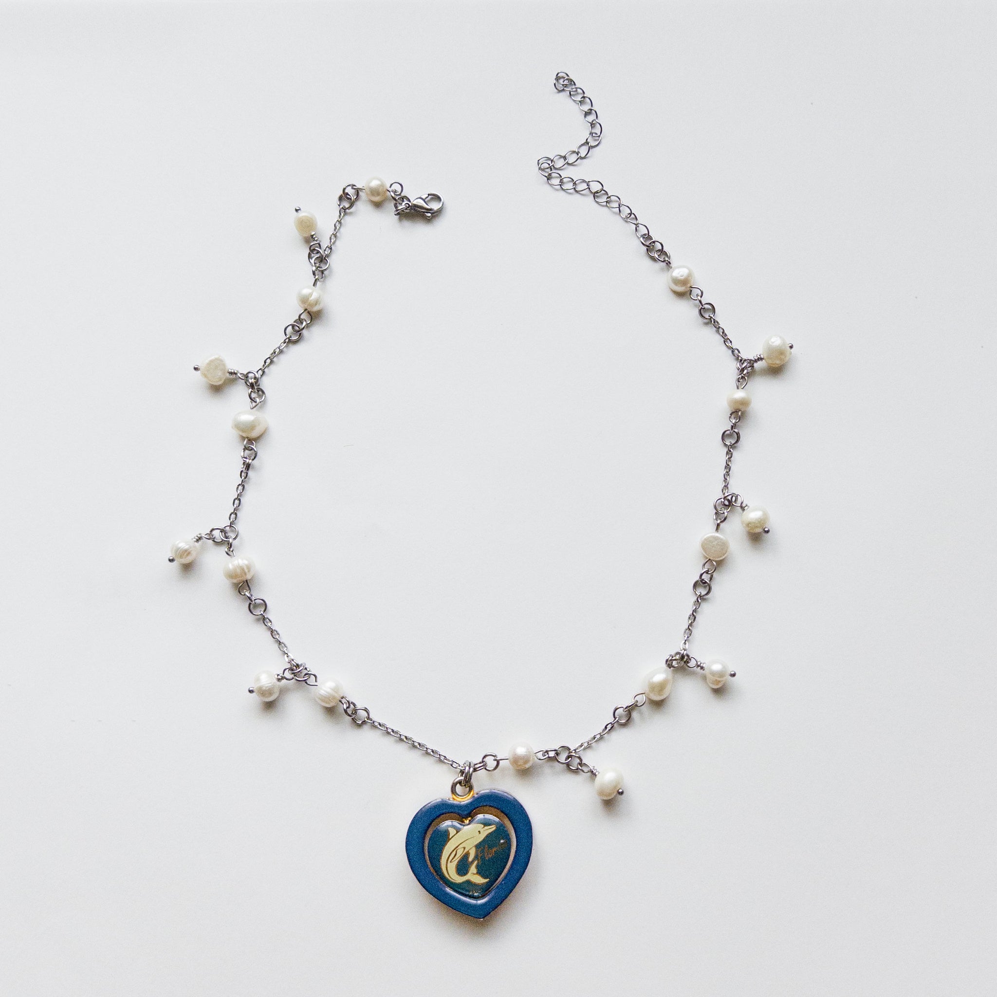 pearl necklace with a spinning heart pendant. the pendant has a white dolphin and text that said "florida".