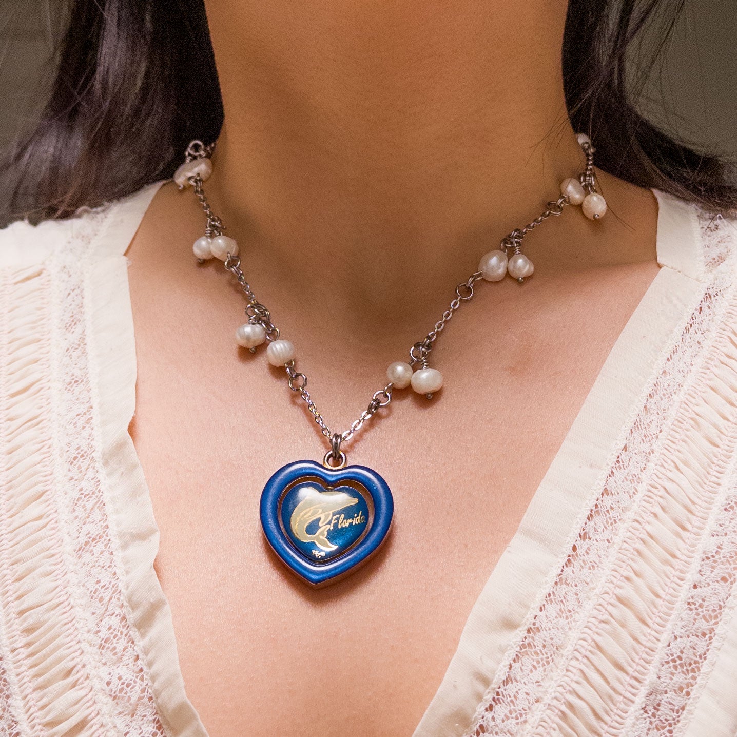 pearl necklace with a spinning heart pendant. the pendant has a white dolphin and text that said "florida".